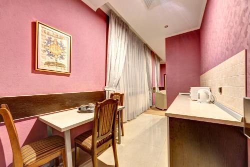 um quarto com paredes cor-de-rosa, uma mesa e cadeiras em Terra Nova Sport&Spa Hotel em Hatne