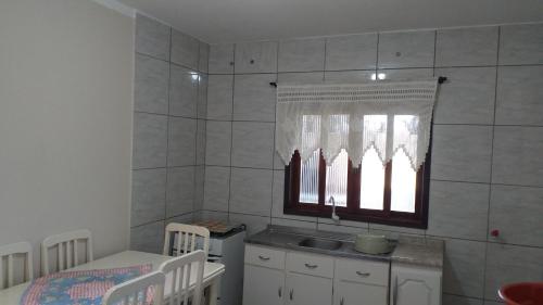 eine Küche mit einem Fenster, einem Waschbecken und einem Tisch in der Unterkunft valdemiro flores in São Francisco do Sul