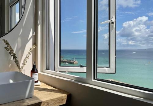 a bathroom with a window with a view of the ocean at Harbour View House in St Ives