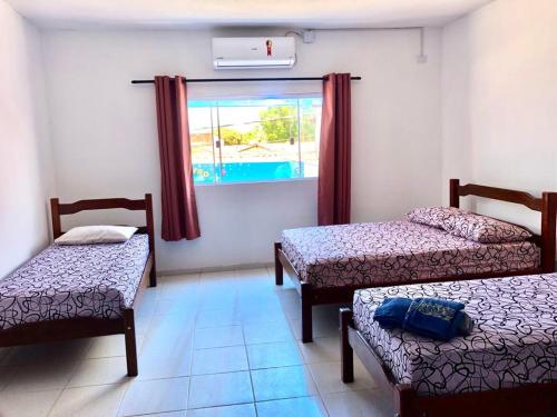 a room with two twin beds and a window at Hostel Família Carvalho in Barreirinhas