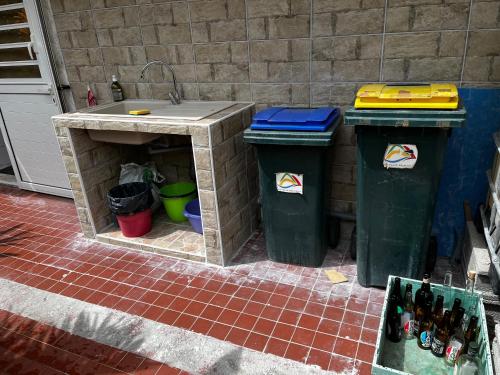 a outdoor kitchen with two trash cans and a sink at L'Escale du Mouillage in Saint-Pierre