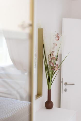 a vase of flowers sitting on a table next to a mirror at Apartman Stari Toranj III in Vukovar