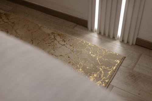 a gold rug on a wooden floor next to a window at Apartman Stari Toranj III in Vukovar