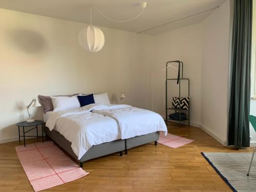 1 dormitorio con 1 cama con sábanas blancas y alfombras rosas en Charmante Stadtwohnung im Textilviertel, en Augsburg