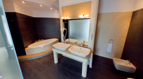 a bathroom with two sinks and two mirrors at Hotel Olympic Spa & Wellness in Ustroń