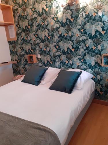 a bed with two blue pillows in a room with a wallpaper at Ma Campagne - Le Jardin in Auberville