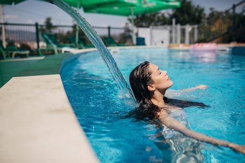 a woman is in a swimming pool with a splash at Freya SPA Apartments in Niš
