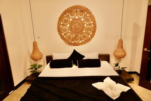 a bedroom with a large white bed with black pillows at The Jini House in Ahangama