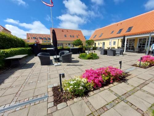 a courtyard with pink flowers and a building at Toftegården Guesthouse - Rooms in Skagen