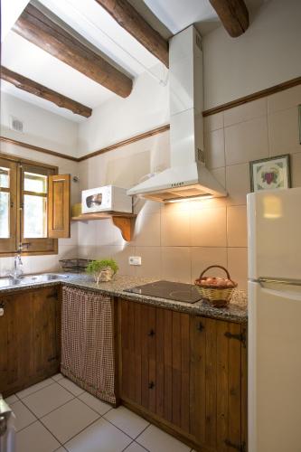 a kitchen with wooden cabinets and a white refrigerator at Mas Pratsevall in Taradell