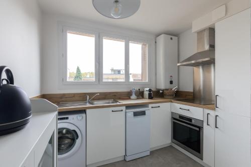 une cuisine avec des armoires blanches et une laveuse et une sécheuse dans l'établissement Frida - 2 chambres - Balcon, à Toulouse