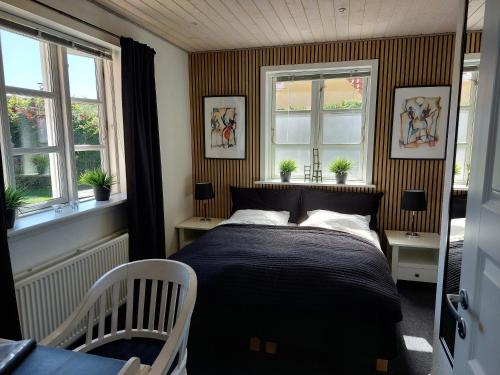 a bedroom with a bed and two windows at Toftegården Guesthouse - Apartments & Rooms in Skagen