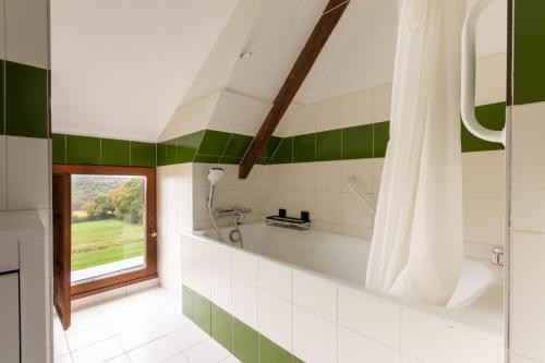 baño con bañera y azulejos verdes y blancos en Kerguestenen, en Inguiniel