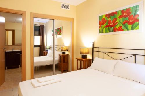 a bedroom with a white bed and a mirror at Apartamentos Playamarina in Isla Canela