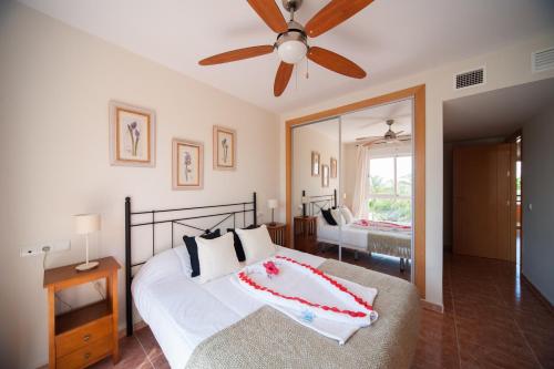 a bedroom with a bed with a ceiling fan and a mirror at Apartamentos Paraiso Playa in Vera