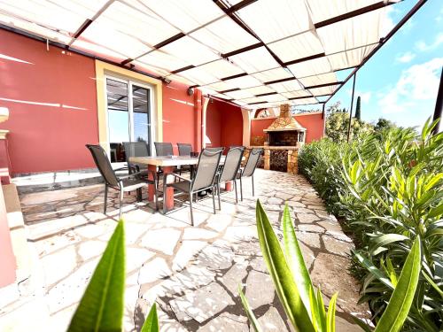 a patio with a table and chairs and a fireplace at GKK House private swimming pool luxury house in Skriperón