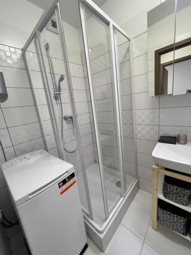 bagno con doccia e frigorifero bianco di Seaforth Apartment a Siófok