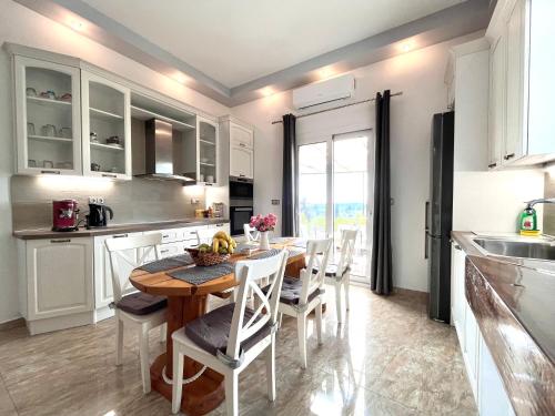 a kitchen with a wooden table and white cabinets at GKK House private swimming pool luxury house in Skriperón