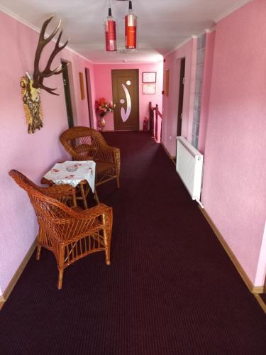 corridoio con sedie, tavolo e pareti rosa di Pensiunea Floare de Bucovina a Frasin