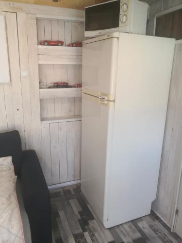 a white refrigerator with a microwave on top of it at Flor de Loto Romantic Woodhouse casita camping in Aguatona