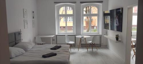 a bedroom with a bed and a table and windows at Apartament na weekend in Świdnica