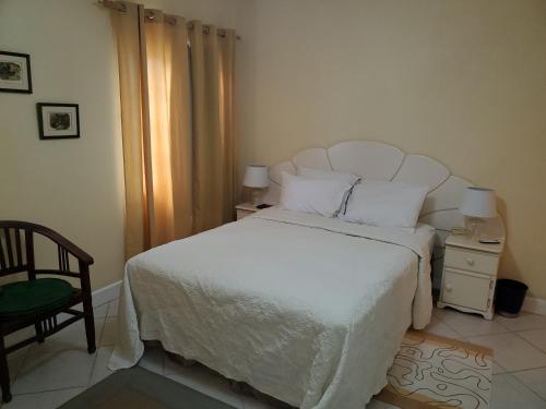 a bedroom with a white bed and a chair at 25 Margate Gardens in Bridgetown