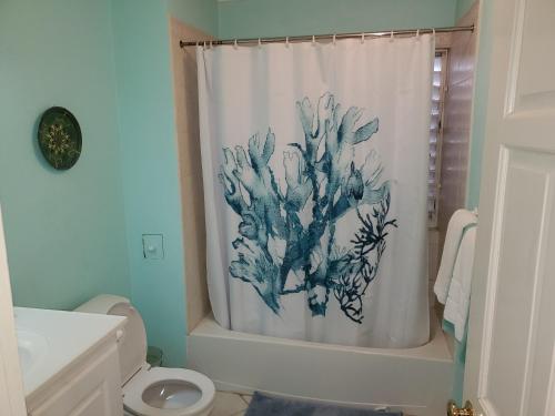 a bathroom with a shower curtain with a painting of a coral at 25 Margate Gardens in Bridgetown