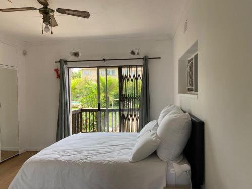 a bedroom with a bed with a ceiling fan and a window at Birch stay in Kempton Park