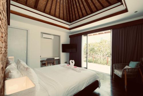 a bedroom with a bed with a white bedspread and a window at Sunset Palms Beach Villa in Jimbaran
