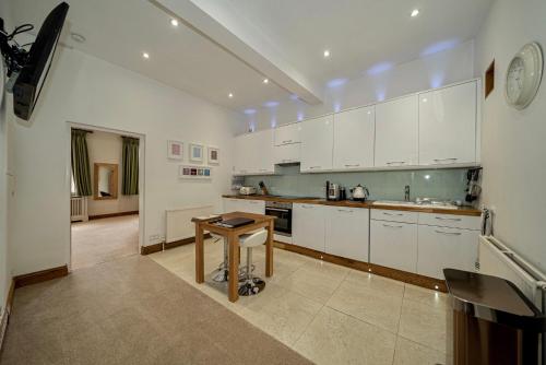 a large kitchen with white cabinets and a wooden table at Serviced Apartments Macclesfield in Macclesfield