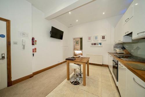 a kitchen with a wooden table in a room at Serviced Apartments Macclesfield in Macclesfield
