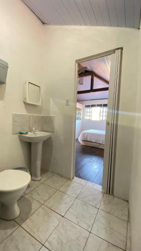 a bathroom with a toilet and a sink and a bed at Aurora Hostel in Pipa