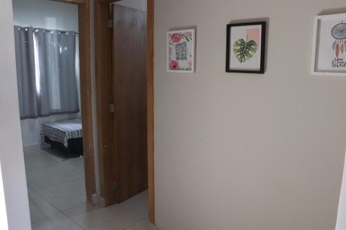 un pasillo con dos cuadros en la pared y una puerta en Casa com 03 quartos tendo 02 com ar condicionado no asfalto a 1,5 km do centro, en Chapada dos Guimarães