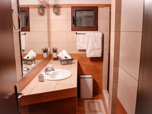 a bathroom with a sink and a mirror and towels at Αντίρρινο - Guest house in Arachova