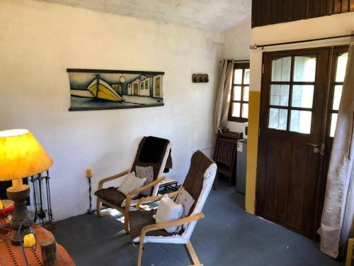 a living room with two chairs and a door at Cuchilla Alta-La Cabaña Celeste in Cuchilla Alta