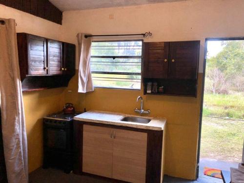 una pequeña cocina con fregadero y ventana en La Cabaña Celeste, en Cuchilla Alta