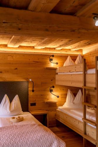 two bunk beds in a room with wooden walls at Das kleine Bio Hotel Tiefenbach in Schladming