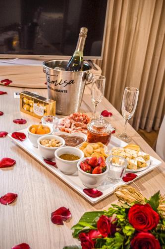 a tray of food on a table with a bottle of wine at Nobile Inn London Anápolis in Anápolis