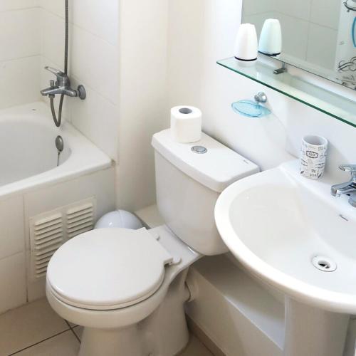 a white bathroom with a toilet and a sink at Departamento Exclusivo Talca in Talca