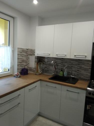 eine Küche mit weißen Schränken und einem Waschbecken in der Unterkunft Klimatyczne mieszkanie in Hajnówka