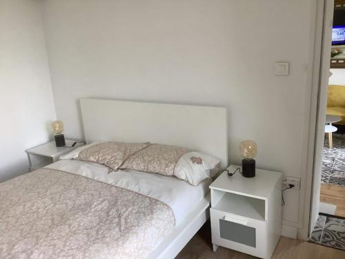 a white bedroom with a bed and a night stand at Le Chalet du RDC in Bagnoles de l'Orne