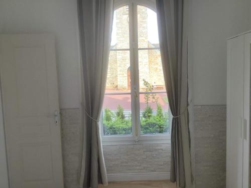 a large window with curtains in a room at Le Chalet du RDC in Bagnoles de l'Orne