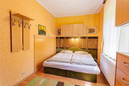 a bedroom with a bed in a room with yellow walls at Visegrád Vendégház-Apartman in Visegrád