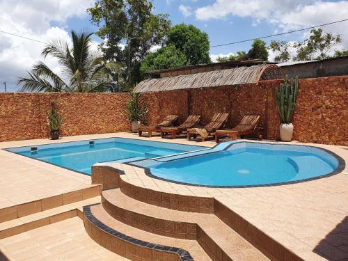 a swimming pool with stairs next to a brick wall at Triton Apartments in Pwani Mchangani