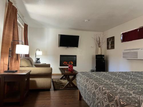 a hotel room with a bed and a couch and a fireplace at TimberLodge Inn in Pinetop-Lakeside