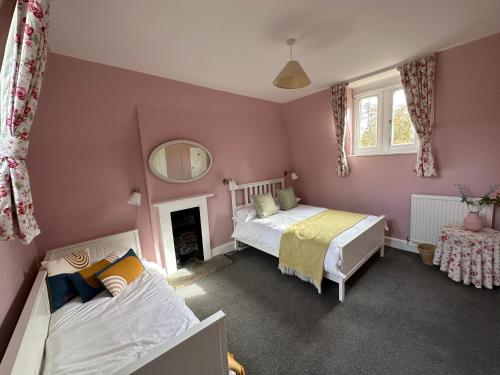 a bedroom with two beds and a mirror at Historic 2 bed gatehouse in private parkland in Brockenhurst