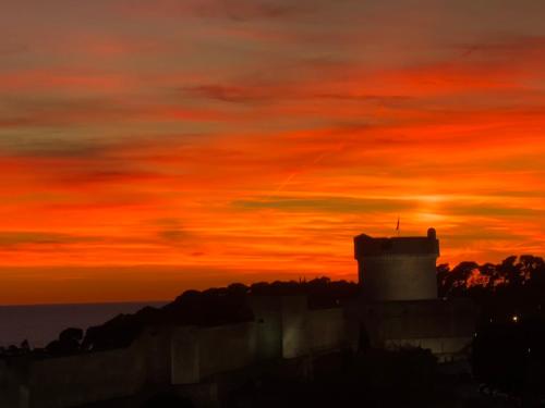 a sunset with a tower in the foreground at Guest House Enny in Dubrovnik