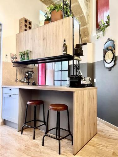 a kitchen with two bar stools at a counter at 300yr old, self catering, tiny house in Victoria Centre, Gozo in Victoria
