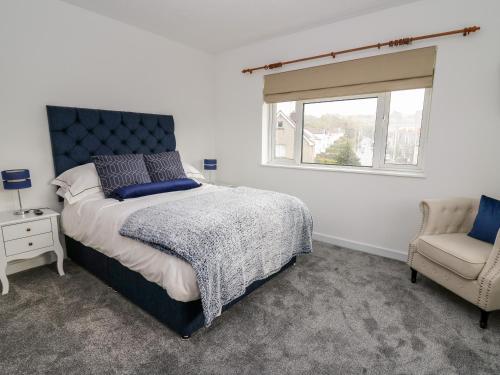 a bedroom with a bed and a chair and a window at Ty Melyn in Aberystwyth