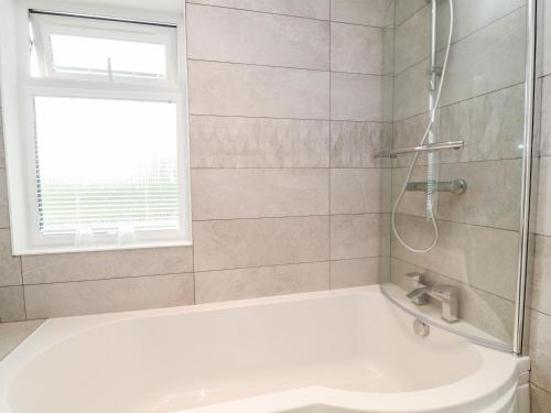 a bathroom with a shower and a tub and a sink at Woodpecker Lodge in Beaworthy